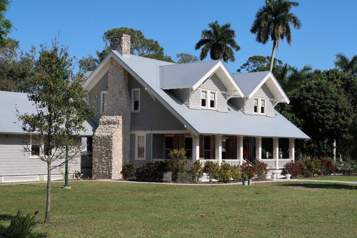 house with two dormers, a porch, and a brick chimney